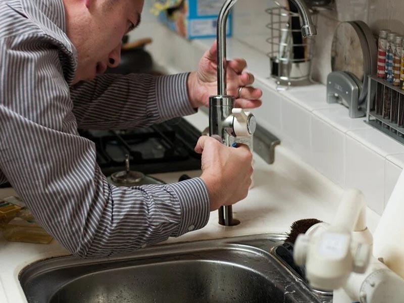 man fixing the plumbing on a kitchen sink