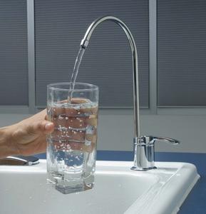 someone pouring water into a clear glass